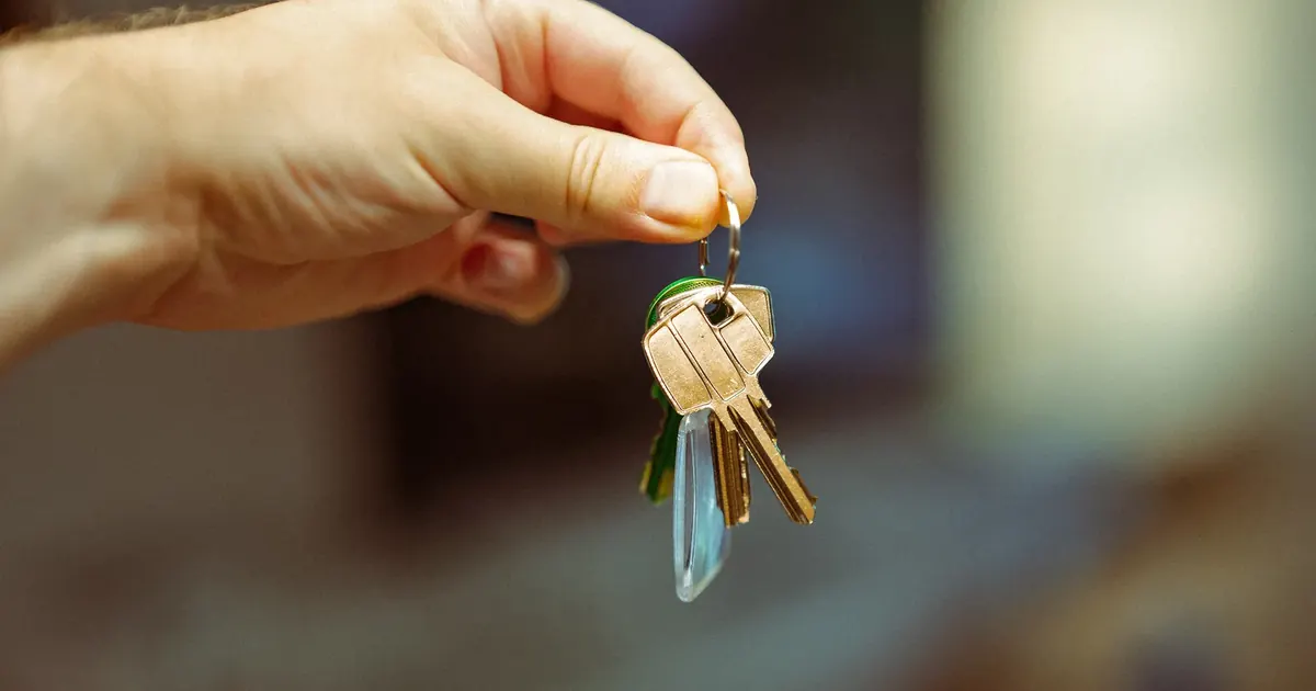 Administrar tú el arriendo o pagar una inmobiliaria Mano entregando un juego de llaves de vivienda — administrar el arriendo o contratar inmobiliaria en Colombia 2026