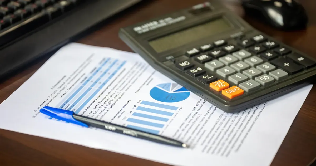 Cómo calcular el impuesto predial en Colombia 2026 Calculadora, informe financiero y bolígrafo sobre un escritorio — cómo calcular el impuesto predial en Colombia 2026