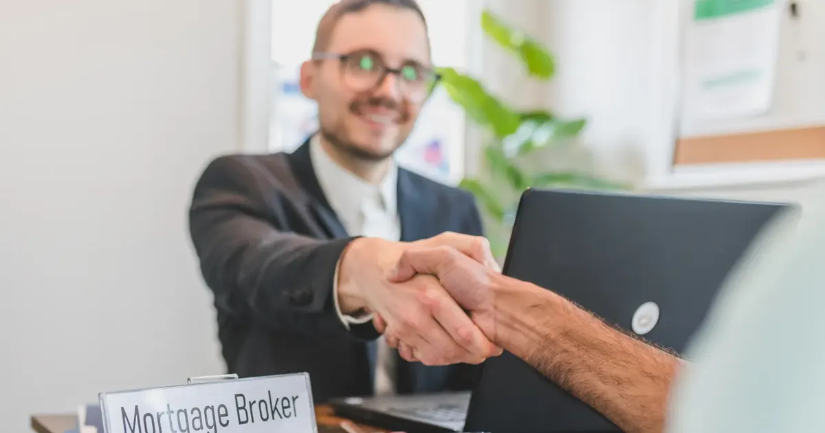 Cuánto te presta el banco para vivienda en Colombia 2026 Asesor hipotecario estrechando la mano de un cliente en una oficina — cuánto presta el banco para vivienda en Colombia 2026