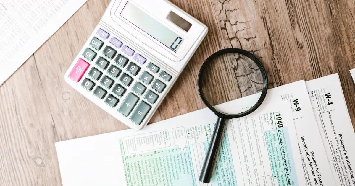Cómo calcular el cap rate paso a paso Calculadora y lupa sobre documentos financieros — cómo calcular el cap rate de un inmueble