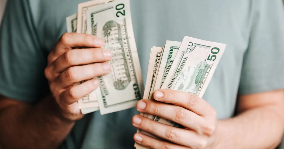 Manos con dinero en efectivo — compra de cartera hipotecaria frente a un CDT 2026