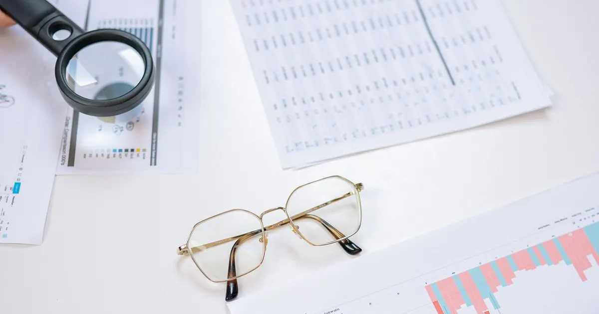 Estudio de títulos 2026: cómo no comprar un problema Lupa y gafas sobre documentos en un escritorio — estudio de títulos de un inmueble en Colombia