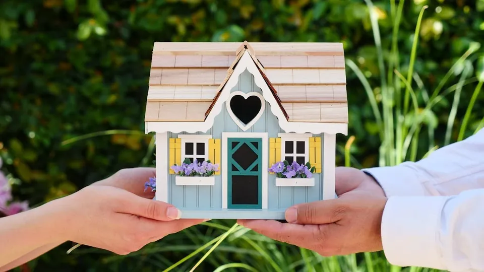 Manos protegiendo una casa: rentabilidad inmobiliaria real