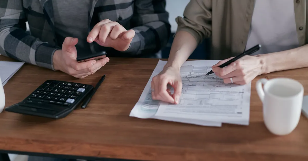 Pareja revisando formularios tributarios con calculadora — retención en la fuente por arrendamientos en Colombia 2026